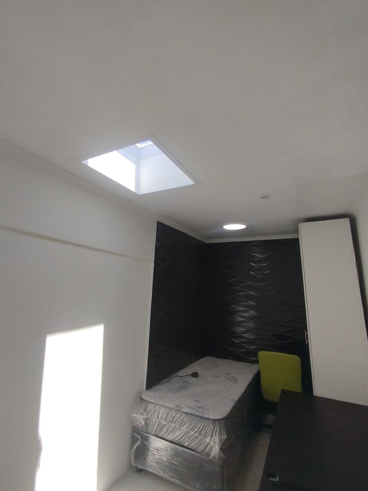 Bedroom skylight installation — clean white ceiling with bold black feature wall