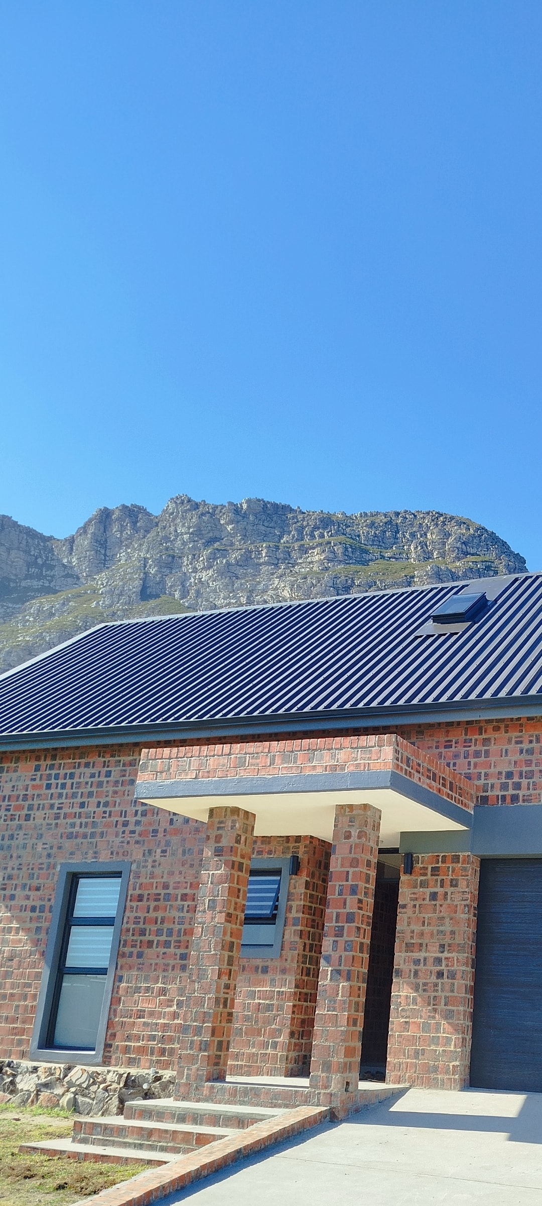 Residential project — brick home with blue metal roof and mountain backdrop