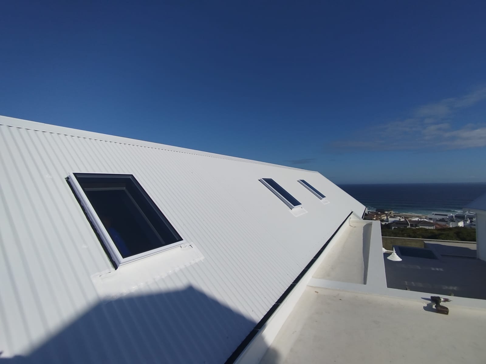 Skylights on a white IBR roof with sweeping ocean views — West Coast installation