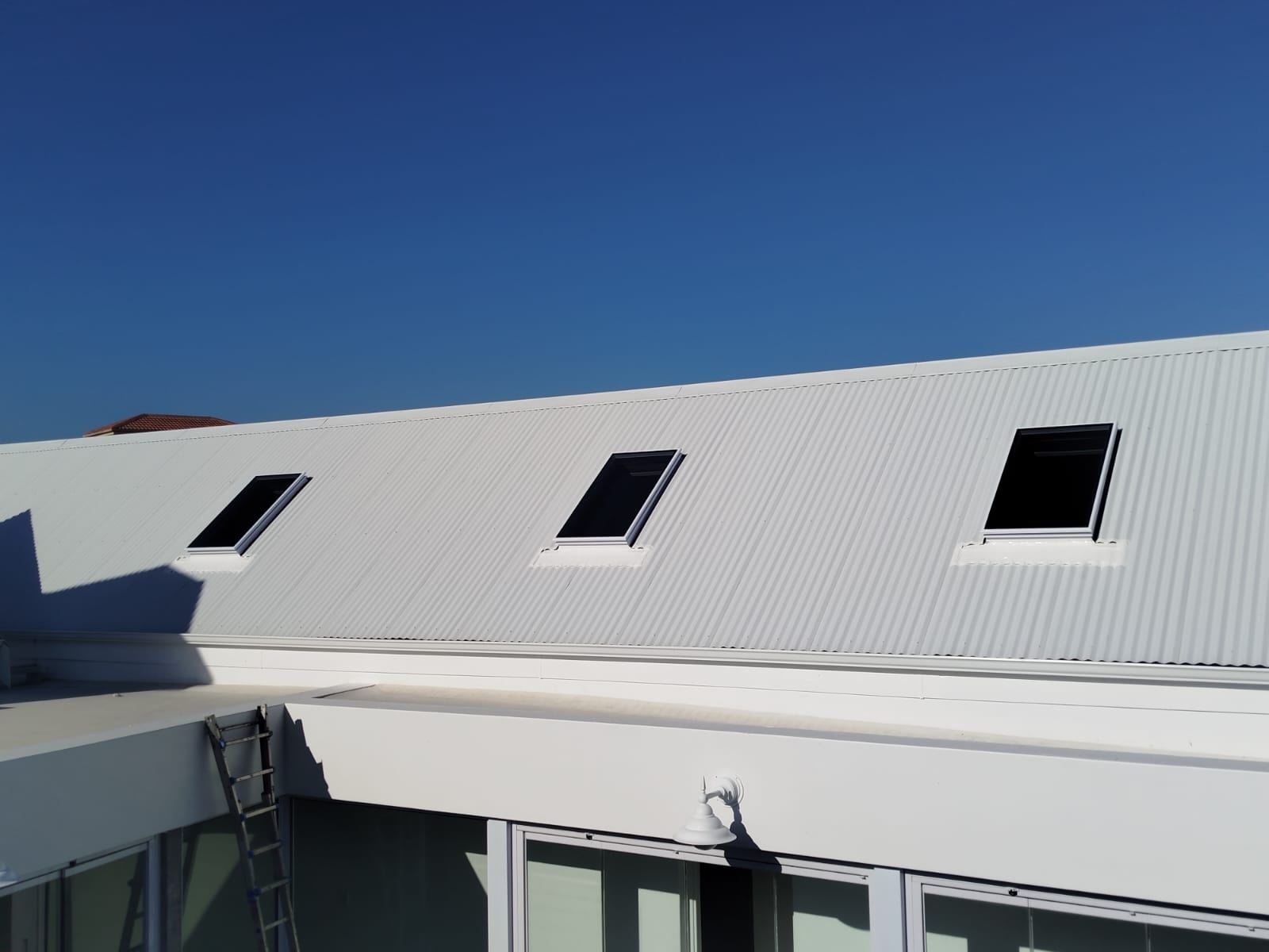 Two skylights on a white IBR roof with mountain suburb backdrop — Southern Suburbs project